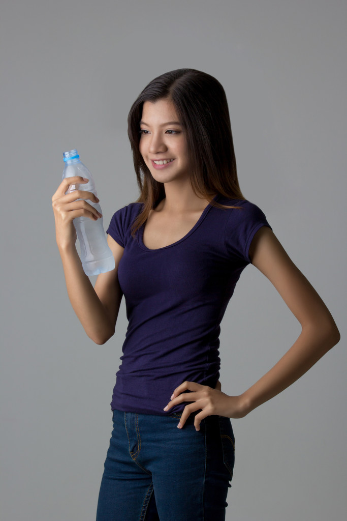 Young Asian woman with drinking water on isolated background